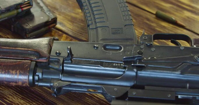 Dolly shot of a male hand attaching magazine to the Kalashnikov assault rifle. Close-up 4k video.