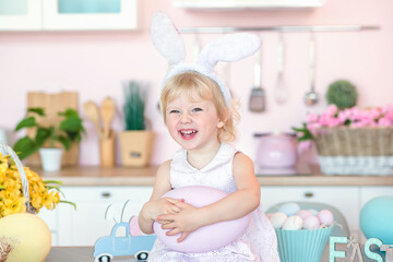 Easter child portrait, funny emotions. Kid with bunny ears in the kitchen in the house laughs...