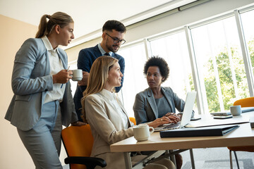 In a cozy, casual office, a group of business professionals monitors stock market activity with keen focus and expertise.