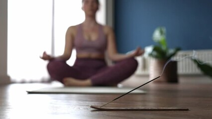 Hand of women in lotus pose while sitting at the floor in the morning sunlight at home. Dolly shot, Concept of relaxation and meditation with incense in the living room beauty