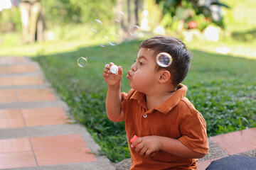 Boy with Down Syndrome Having Fun Blowing Bubbles in His Backyard