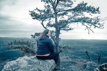 woman sitting on cliff edge after hiking up Cheaha State Park Mountain, highest point in Alabama