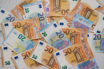 Euro money banknotes. Bundle of 50 and 20 euro bills on white wooden background. Flat lay of euros banknotes