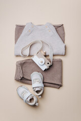 Baby stuff and accessories. Set of knitted clothes - sweater, pants, shoes, wooden camera toy. Baby shower concept. Flat lay, top view. Copy space. Fashion children's clothing, shoes