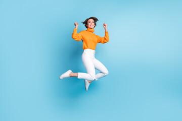 Fototapeta na wymiar Full length photo of lovely young lady jump high celebrate promotion luck dressed stylish orange look isolated on blue color background