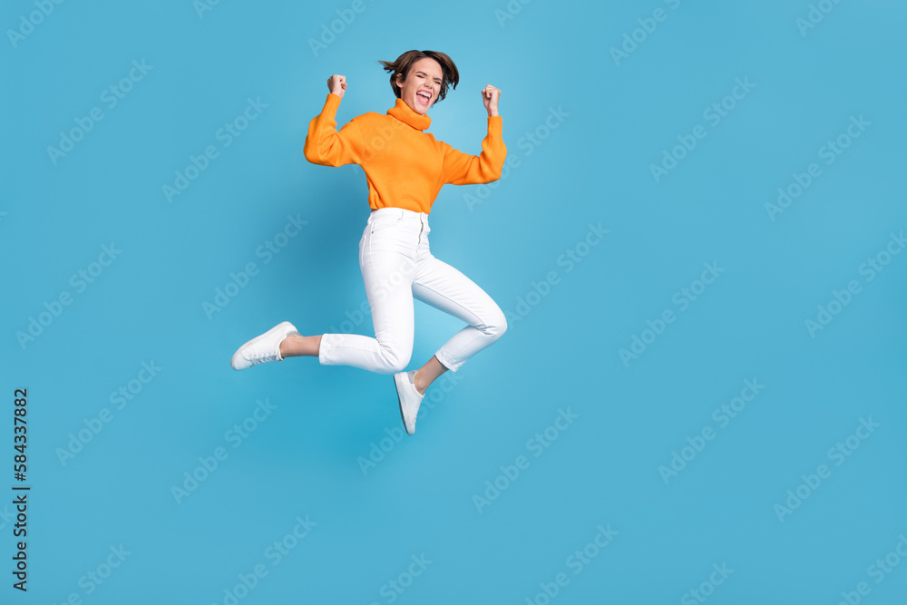 Sticker Full body photo of attractive young woman raise fists shout yeah jump crazy dressed stylish orange look isolated on blue color background