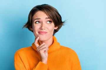 Photo portrait of attractive young woman look thoughtful skeptical empty space wear trendy orange clothes isolated on blue color background