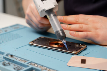 Phone being repaired by an engineer Workshop for the repair of phones and equipment The worker does...
