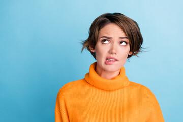 Portrait of minded clueless girl biting lips look empty space contemplate isolated on blue color background