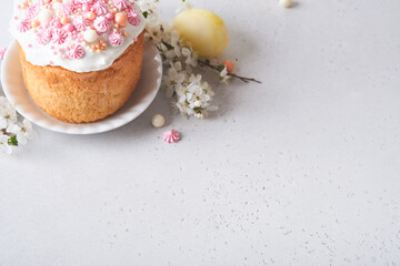 Traditional Easter sweet bread or cakes with white icing and sugar decor, colored eggs and cherry blossom tree branch over white table. Various Spring Easter cakes. Happy Easter day. Selective focus.
