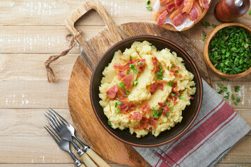Mashed potatoes. Bacon mashed potatoes with green onion, pepper and cheddar cheese in bowl on old wooden backgrounds. Delicious creamy mashed potatoes. Top view.