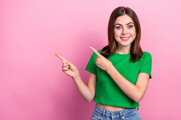 Photo of optimistic satisfied nice girl dressed green t-shirt indicating empty space presenting sale isolated on pink color background