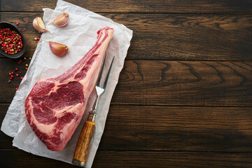 Fresh tomahawk raw steak. Dry aged raw tomahawk beef steak with herbs and salt on old wooden...