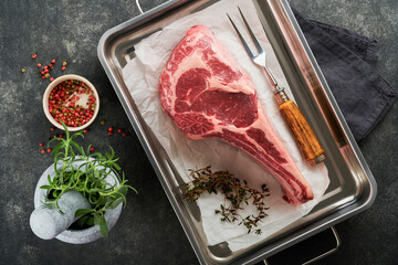 Fresh tomahawk raw steak. Dry aged raw tomahawk beef steak with herbs and salt on old wooden...
