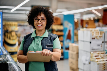 Happy quality control manager working in supermarket and looking at camera.