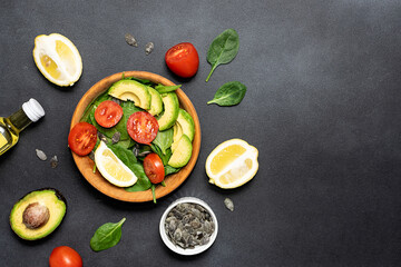 Fresh juicy salad with baby spinach leaves, tomatoes, avocado slices, pumpkin seeds and lemon on...