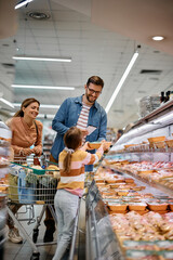 Happy family buying food at refrigerated section in supermarket.