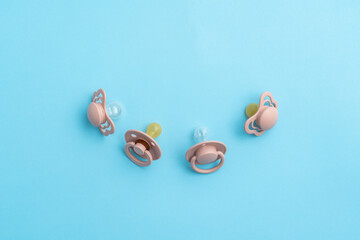 Pacifiers on blue background with copy space, top view of soothers, flat lay
