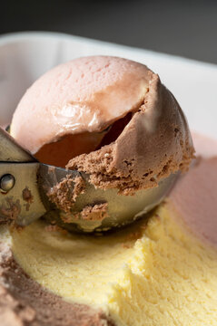 Ice cream ball on colourful pink, chocolate and vanilla ice cream. 