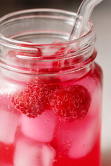 Raspberry refreshing lemonade in mason jar with glass straw, summer cold drink.