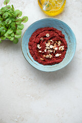 Turquoise bowl with beetroot paste on a light-beige stone background, vertical shot, copy space, top view