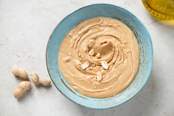 Peanut butter or paste made from ground, dry-roasted peanuts in a turquoise bowl, top view on a...