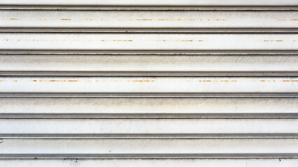 Obraz premium Texture of a metal shutter that acts as a garage door of a small house in a country road, which appears aged, rusty and now devoid of any trace of paint