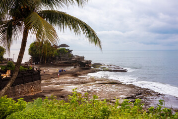 Tanah lot hindu temple seen from a palm tree on Bali island, Indonesia