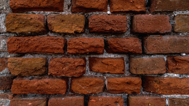 Texture of an aged but relatively recent bare brick wall, made up of bricks of a beautiful vivid color and already free of any cement residue