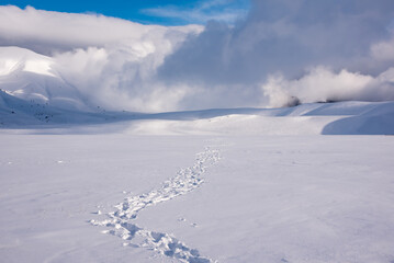 Winter landscape, footprints path in snow valley in bright sunny day