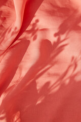 Natural pink fabric background with floral shadows on sunny day. Vertical photo