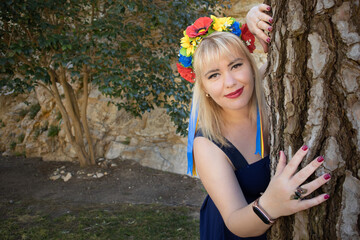 Beauty woman with a wreath on her head near a tree as a symbol of spring and Ukraine. Copy space