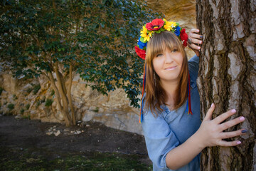 A woman with a wreath on her head near a tree as a symbol of spring and Ukraine's freedom. Copy space