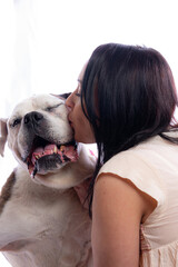 Sweet image of woman kissing bulldog on white background