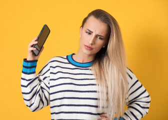 Annoyed girl on the phone, isolated on yellow background. Annoying woman talking. Nuisance and smartphone