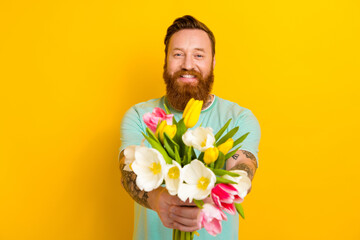 Photo of positive man wear trendy green clothes greeting giving you fresh flowers isolated on...