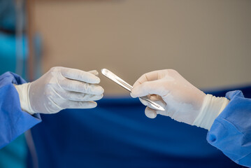 Team of surgery doctor in Operating Room hold hands scalpel surgical blade give to Surgeons During...
