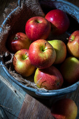 Red apples in a metal bowl on a wooden table