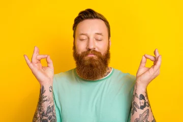 Foto op Canvas Portrait of calm kind candid man wear trendy green clothes enjoy free time yoga practice isolated on yellow color background © deagreez