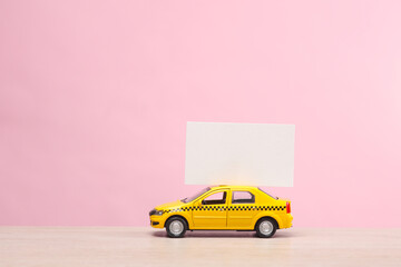 Miniature taxi car with a white business card on a pink background