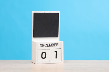 White wooden block monthly calendar with the date december 1 on the table, blue background. Planning, deadline