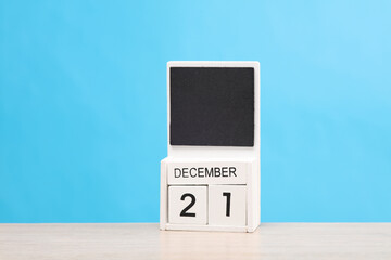White wooden block monthly calendar with the date december 21 on the table, blue background. Planning, deadline