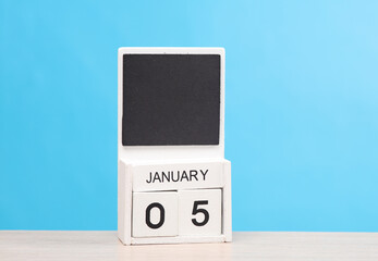 White wooden block monthly calendar with the date january 05 on the table, blue background. Planning, deadline