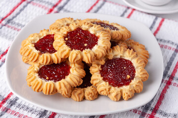 cookies with raspberry jam on a white plate and a checkered napkin, on the table