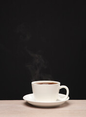 White ceramic cup with hot coffee, steam on a black background