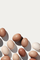 Easter eggs trend pattern on white background shadow at sunlight. Chicken eggs with beige gradient color eggshells, food Easter festive concept, top view, aesthetic flat lay minimal style
