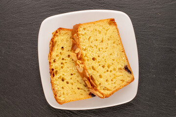 Two pieces of sweet homemade raisin cake with white saucer on slate stone, macro, top view.