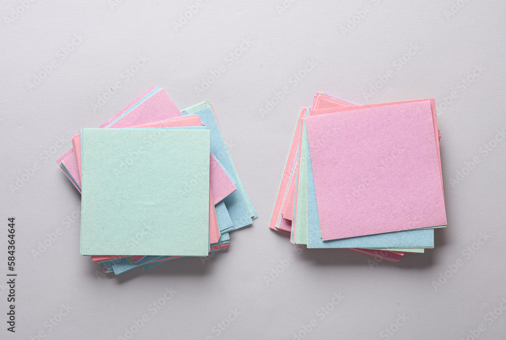 Poster stacks of colored square memo sheets of papers on gray background. top view