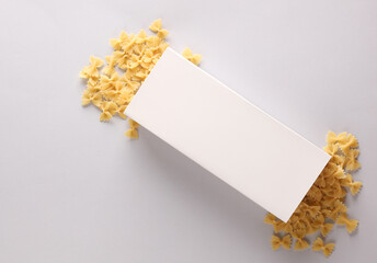 Mockup of a white box with scattered pasta bows on a gray background. Top view. Template for design