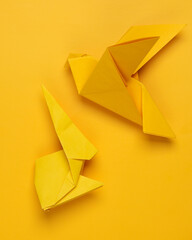 Yellow origami rabbit and dove on yellow background